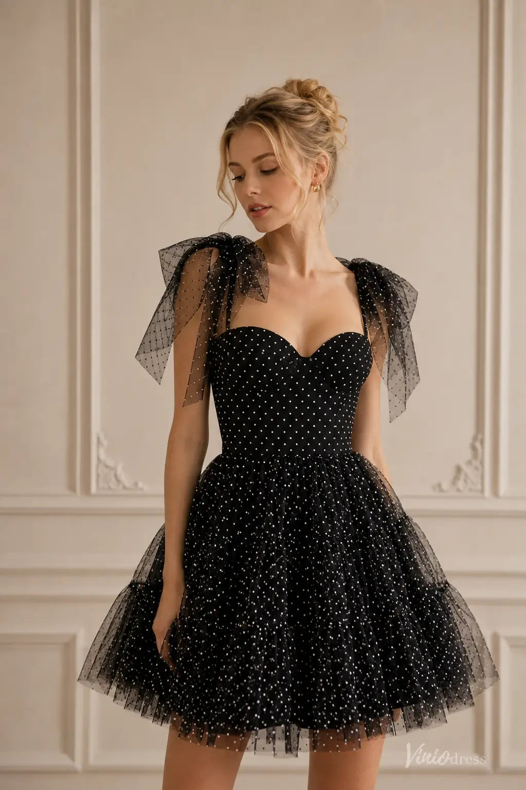 Black strapless homecoming dress with white polka dots, spaghetti straps, and a voluminous ruffled tulle skirt.
