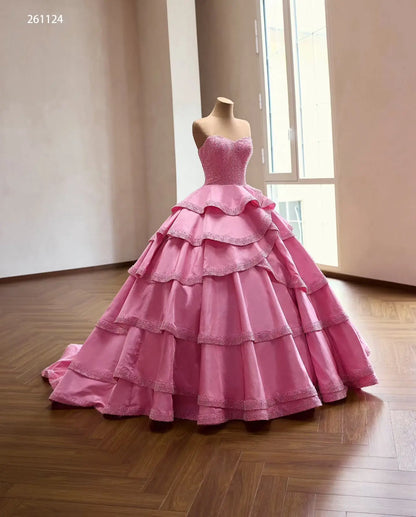 Pink strapless quinceañera dress with a pearl-beaded corset and a voluminous tiered ruffle skirt with beaded edges.