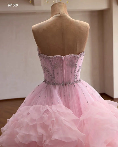 Back view of a pink tulle quinceanera ball gown with a crystal-beaded corset bodice and cascading waterfall ruffles.