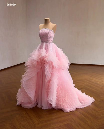 Pink tulle quinceañera ball gown with cascading waterfall ruffles and a crystal-beaded fan corset bodice.