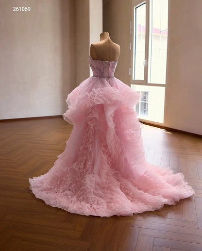 Pink tulle quinceañera ball gown with cascading waterfall ruffles and a crystal-beaded corset bodice on a mannequin.