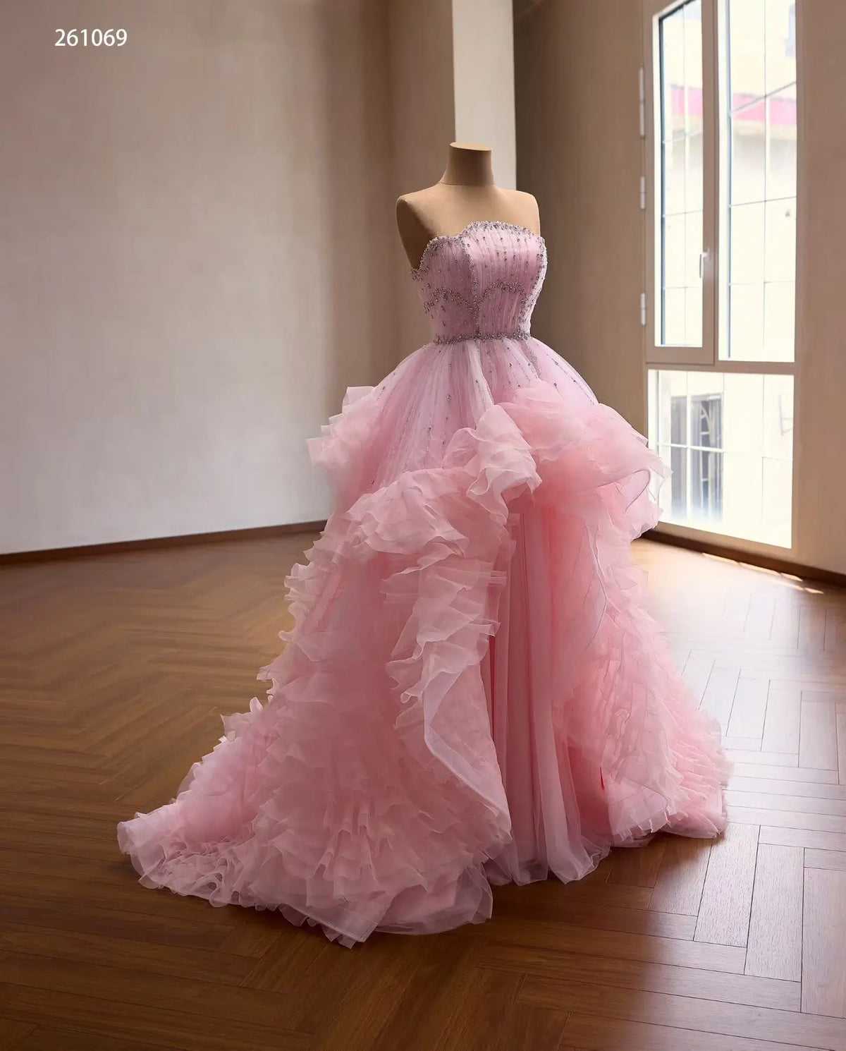 Pink tulle quinceañera ball gown with a crystal-beaded fan corset and cascading waterfall ruffle skirt.
