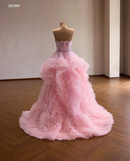 Pink tulle quinceañera ball gown with a crystal-beaded corset bodice and cascading waterfall ruffle skirt.