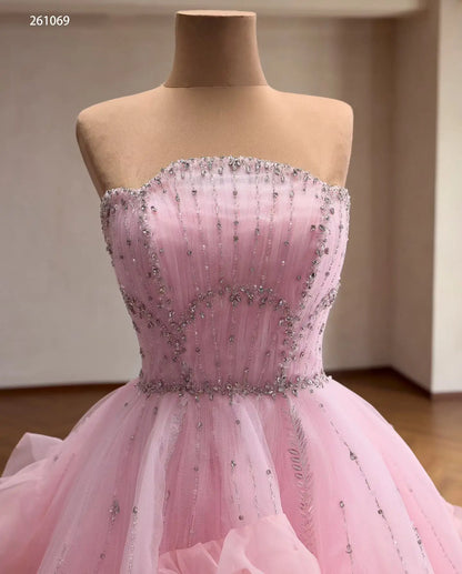 Pink tulle quinceañera ball gown with a crystal-beaded fan corset bodice and cascading waterfall ruffles.