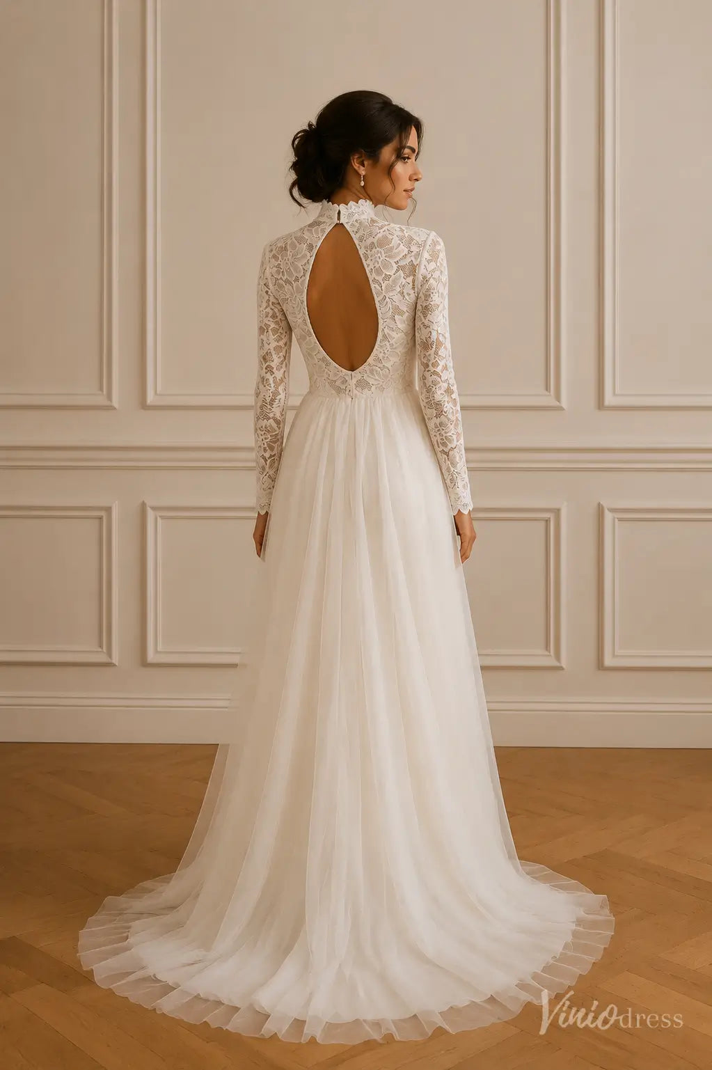 White lace wedding dress with long sleeves, high neck, and a circular open back design with a flowing tulle skirt.