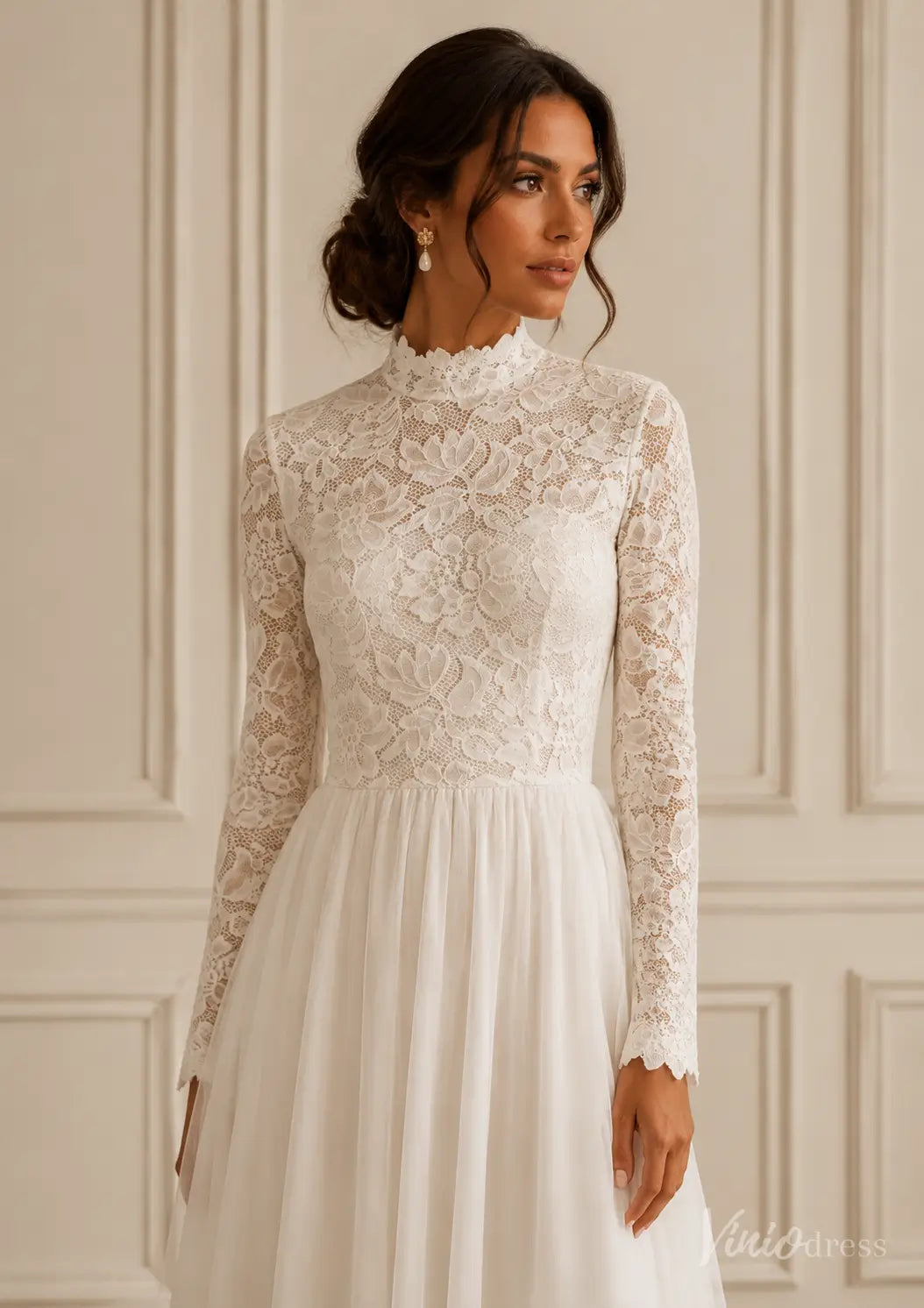 White long-sleeve wedding dress with a high lace neckline, floral lace bodice, and a flowing tulle skirt.