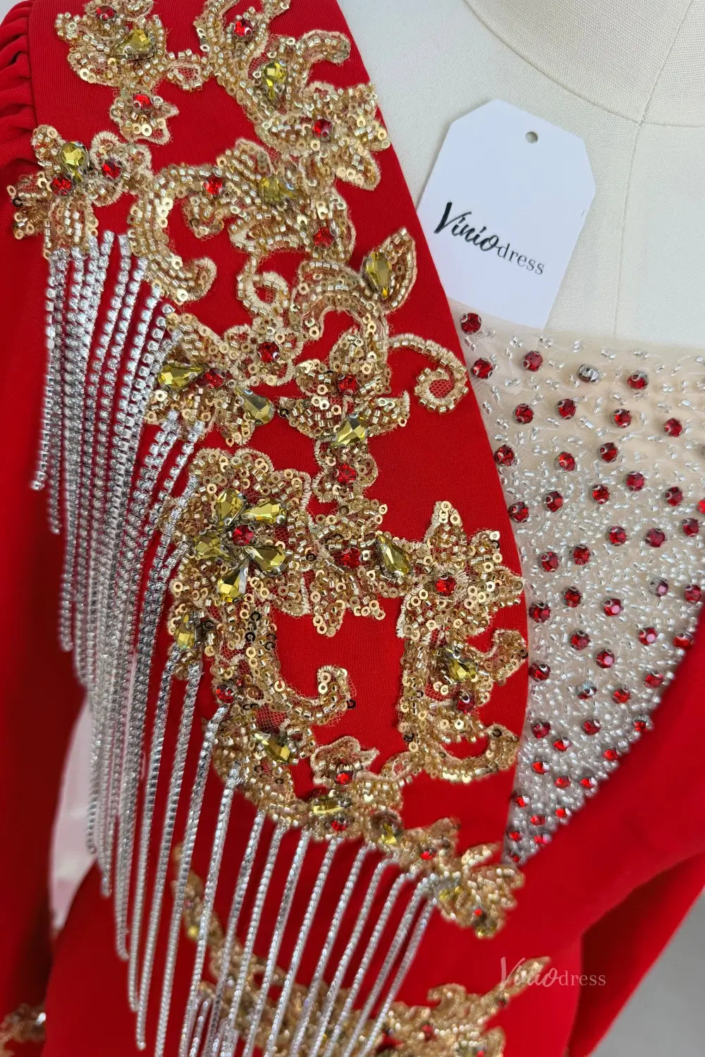 Red evening dress with gold beaded lace, silver fringe, and red rhinestones on a mannequin.