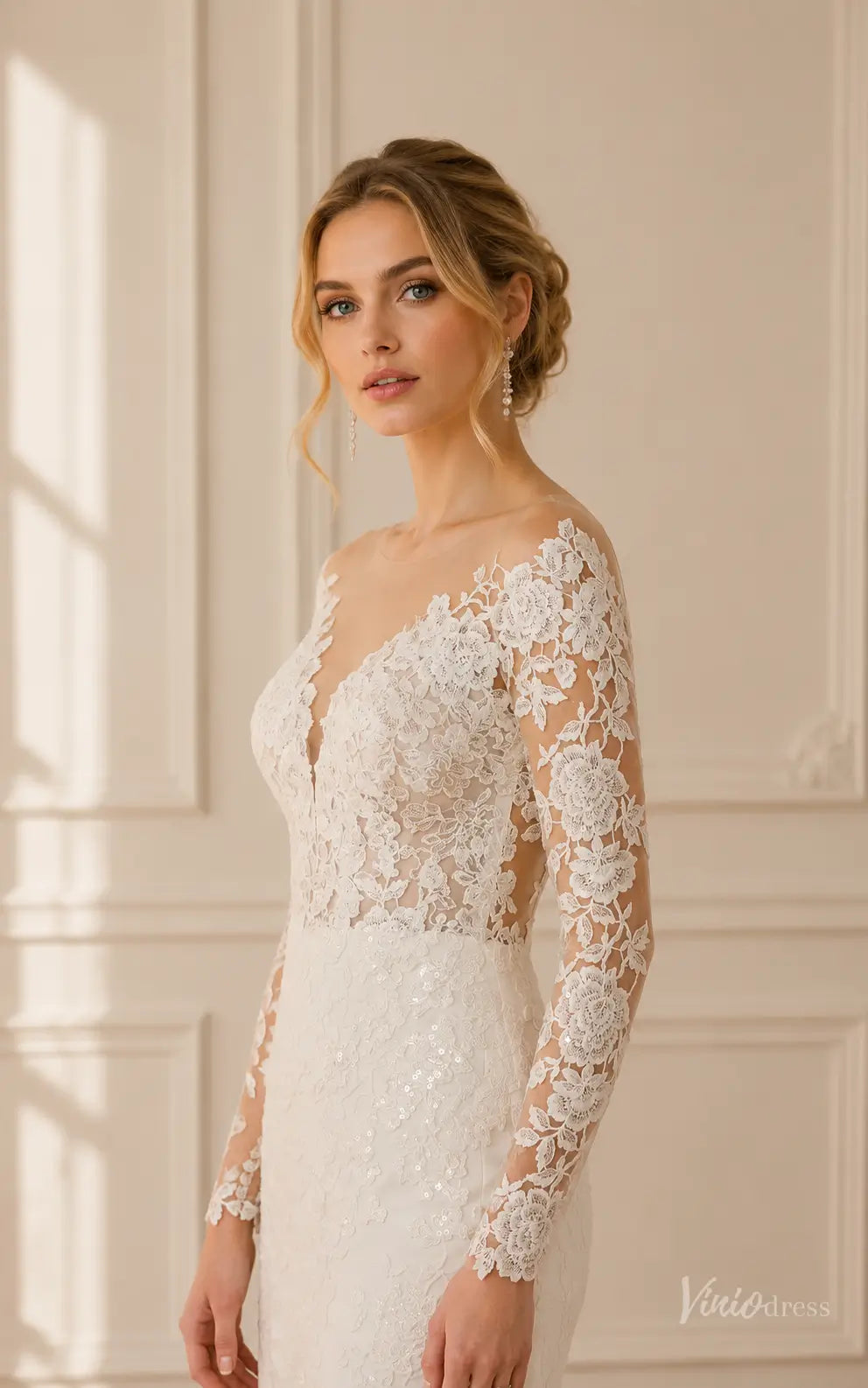 Ivory mermaid wedding dress with long illusion sleeves, delicate floral lace appliqué, and a sheer V-neckline.