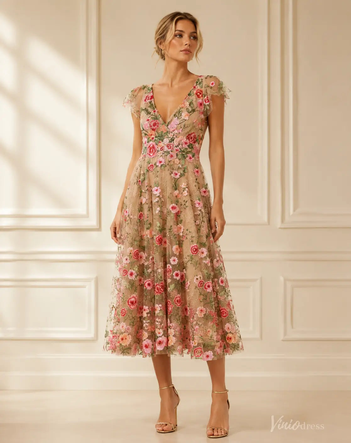Midi length V-neck evening dress in nude mesh with vibrant pink and green floral embroidery and delicate cap sleeves.