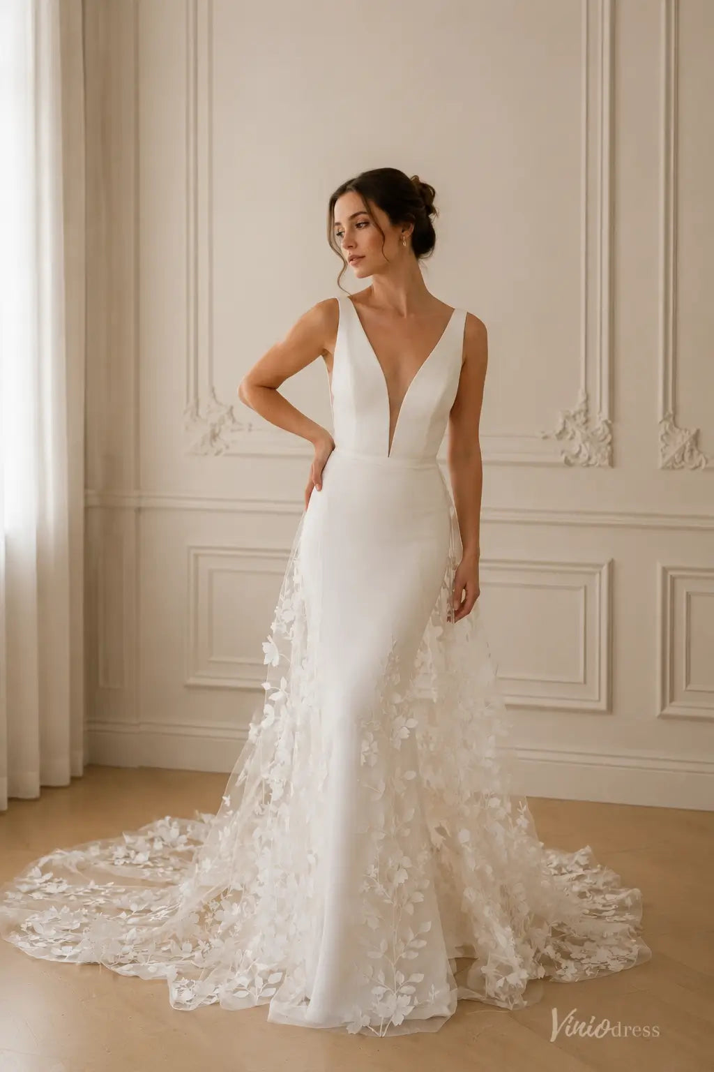 ML192 white V-neck wedding dress with a sleek bodice and a sheer floral applique overskirt and train.