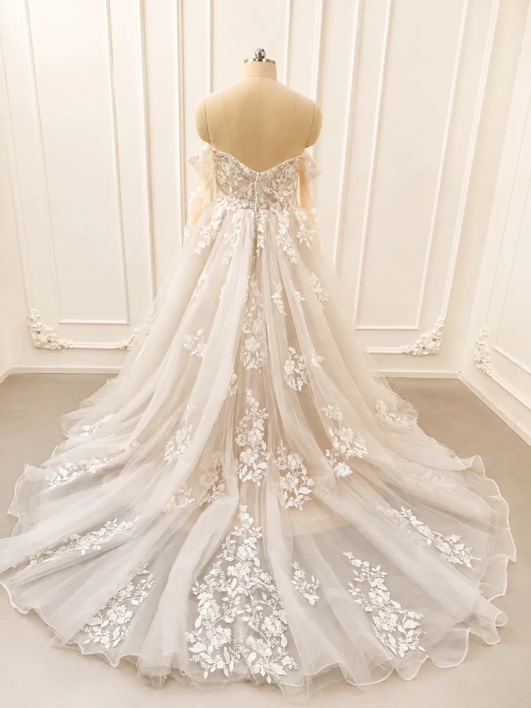 Ivory off-shoulder wedding dress with floral lace bodice, long sleeves, and a dramatic cathedral tulle train.