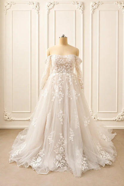 Ivory off-shoulder wedding dress with long lace sleeves, floral appliqué, and a voluminous tulle A-line skirt.