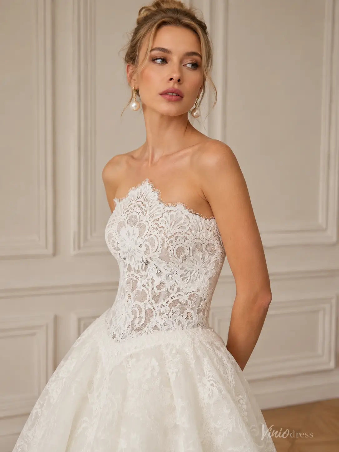 Strapless white lace wedding dress with a fitted bodice and full skirt, featuring intricate floral lace detailing.