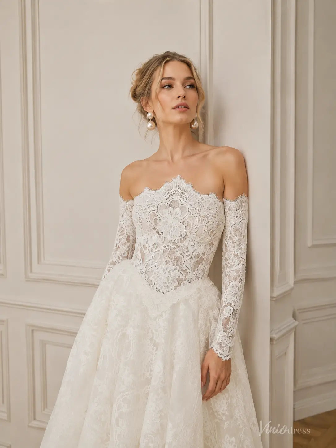 Off-the-shoulder white lace wedding dress with long sleeves and a corset-style bodice, featuring intricate floral patterns.