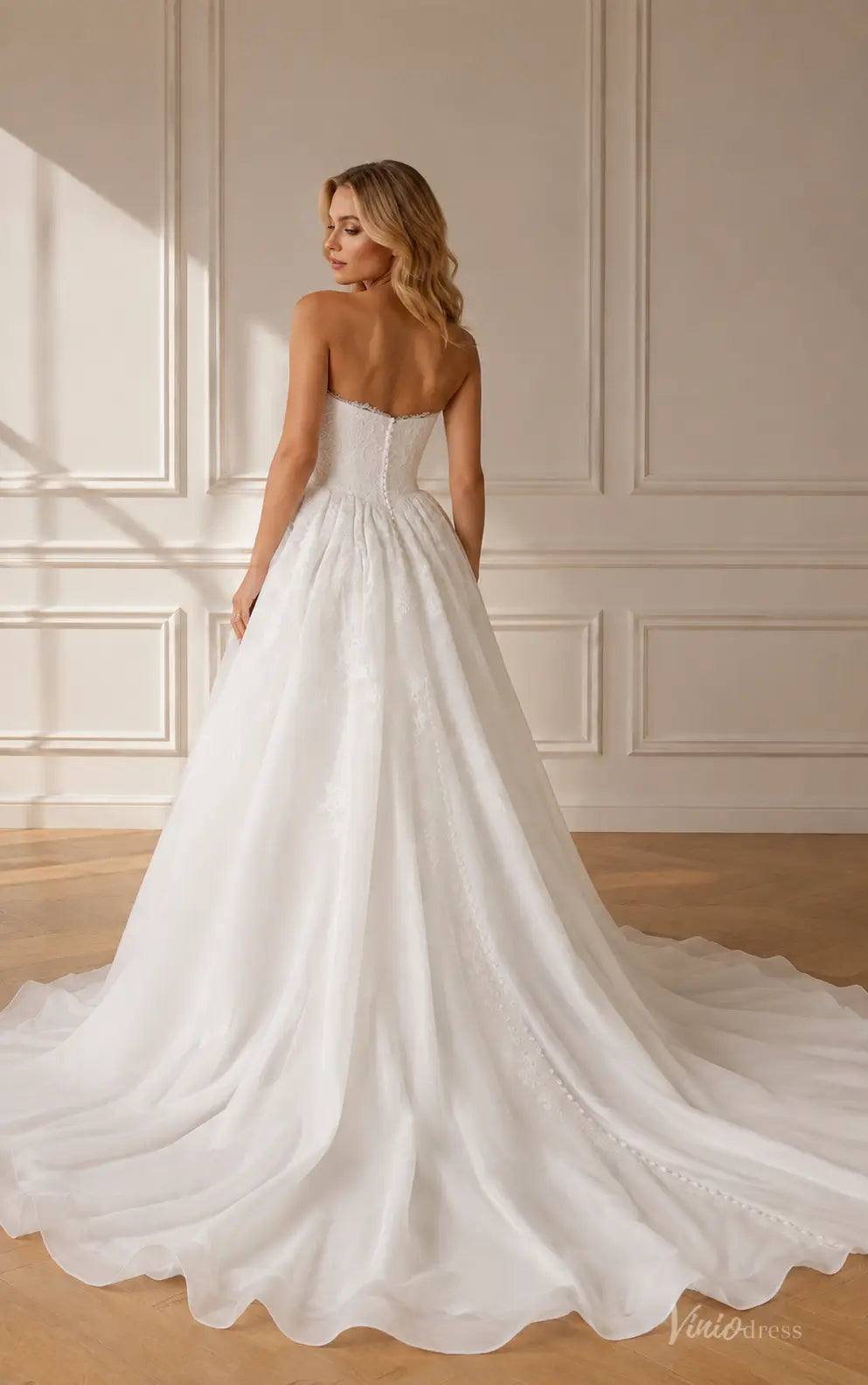 Strapless white A-line wedding dress with lace bodice, full tulle skirt, and a button-up back with a long train.