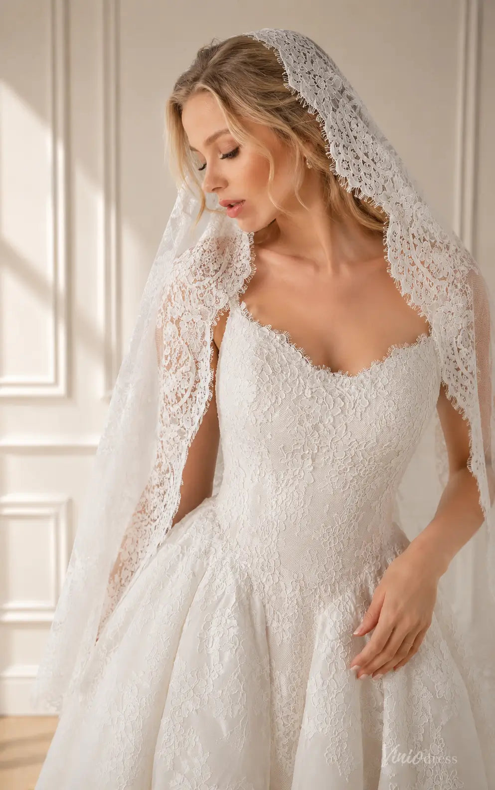 White lace wedding dress with a sweetheart neckline and matching intricate lace veil, featuring a classic bridal silhouette.