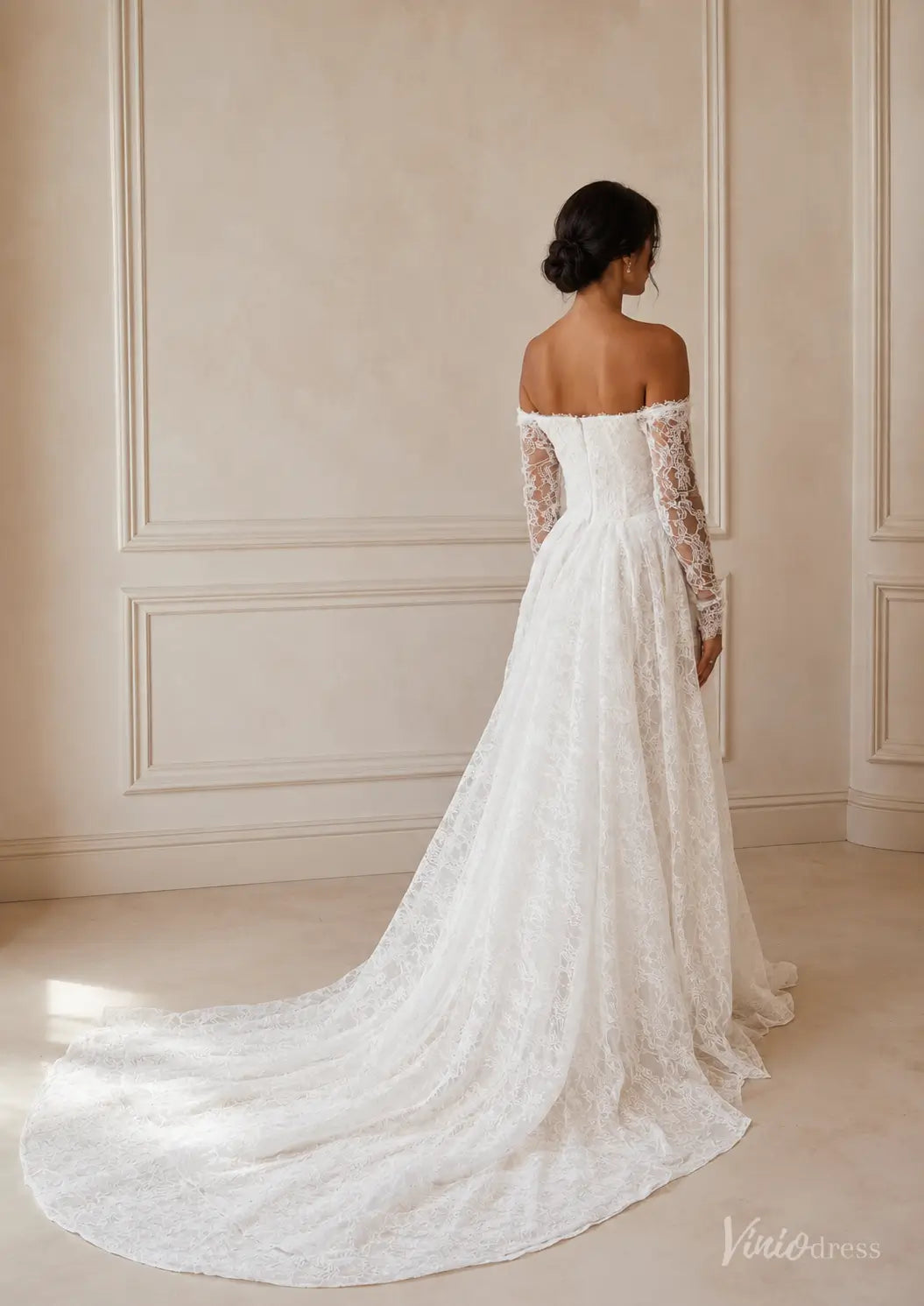 Off-the-shoulder white lace wedding dress with long sleeves and a flowing floor-length train.