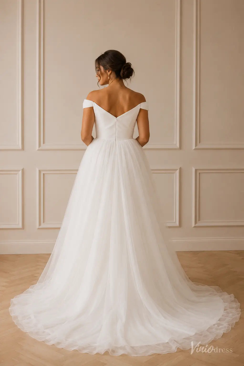 White off-the-shoulder wedding dress with a satin bodice and a flowing tulle A-line skirt.