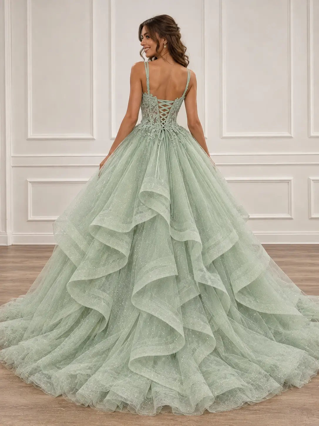 Sage green glitter tulle ball gown with a lace corset back and voluminous ruffled skirt for prom.