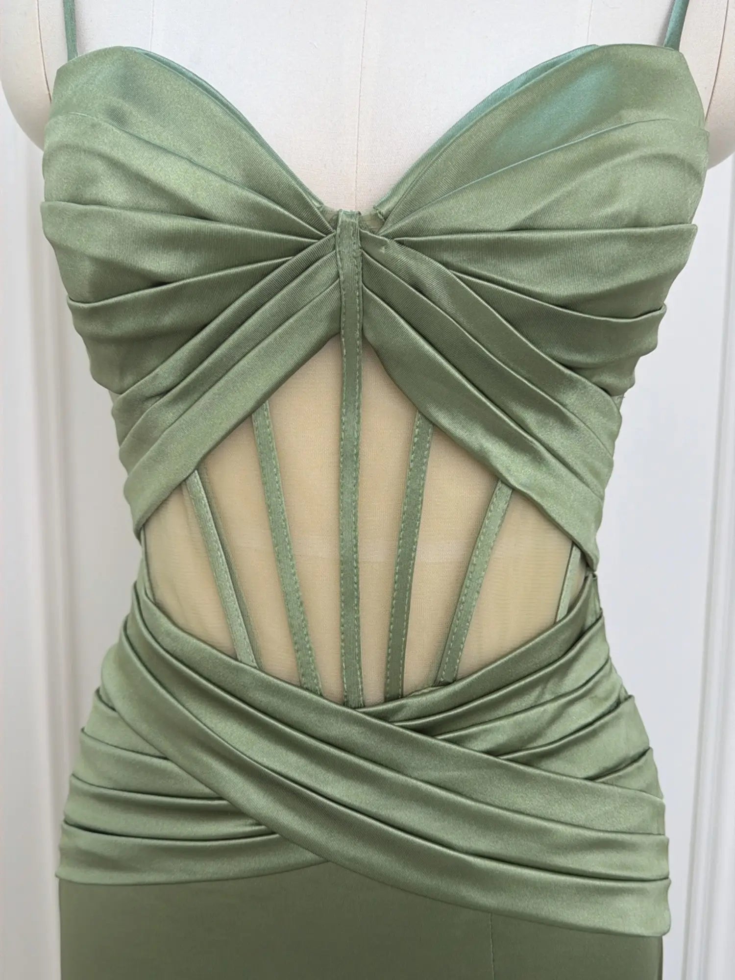 Sage green satin prom dress featuring a corset-style cutout bodice with ruched waist and spaghetti straps.