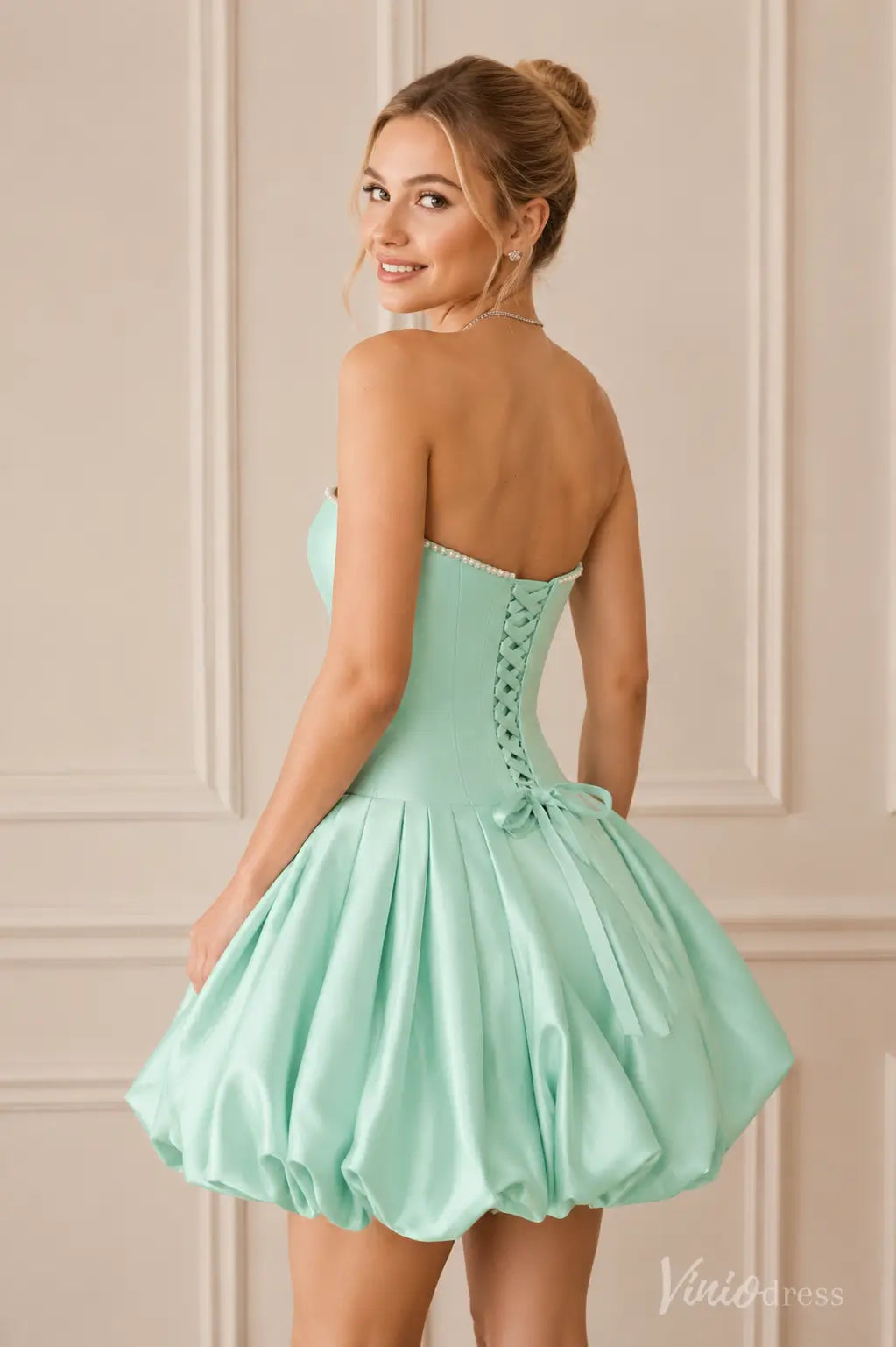 Mint green strapless mini dress with a corset back, pearl trim, and a voluminous pleated bubble skirt.