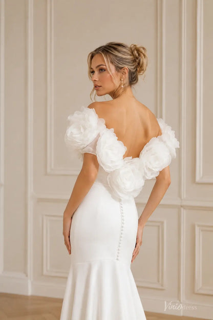 Ivory crepe mermaid wedding dress with off-shoulder neckline, oversized 3D floral accents, and covered back buttons.