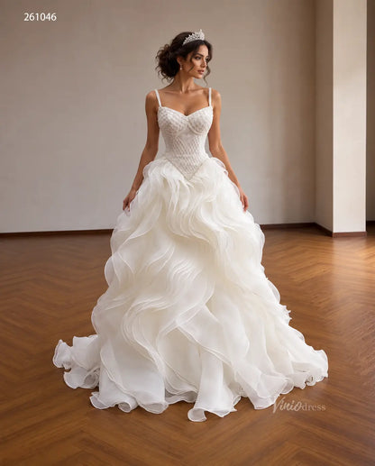 Ivory quinceañera ball gown with a diamond-beaded basque corset, sweetheart neckline, and voluminous sculptural wave ruffles.