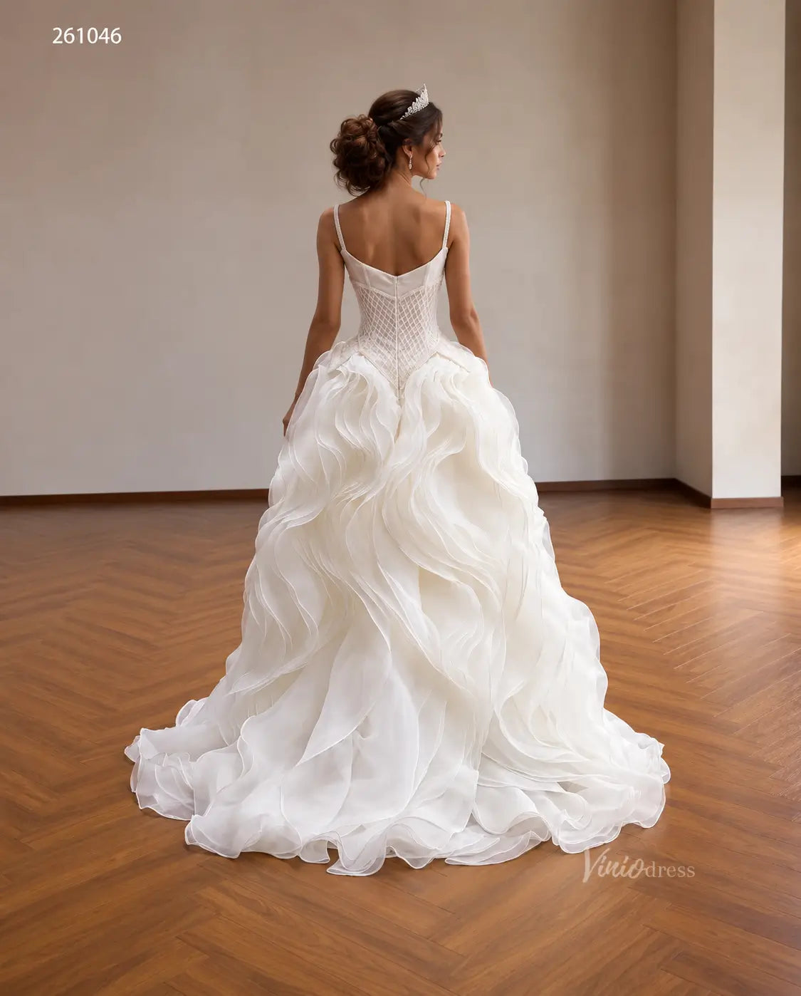 Ivory quinceañera ball gown with a diamond-beaded basque corset and a dramatic sculptural wave ruffle skirt.