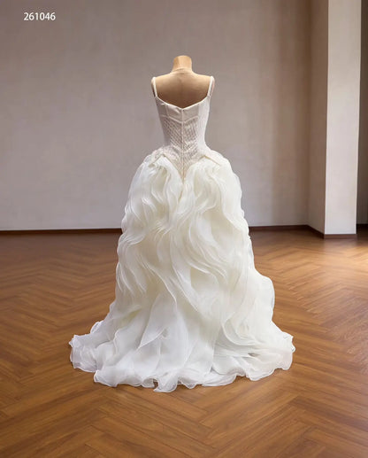 Ivory quinceañera ball gown with a diamond-beaded basque corset and a voluminous skirt of sculptural wave ruffles.