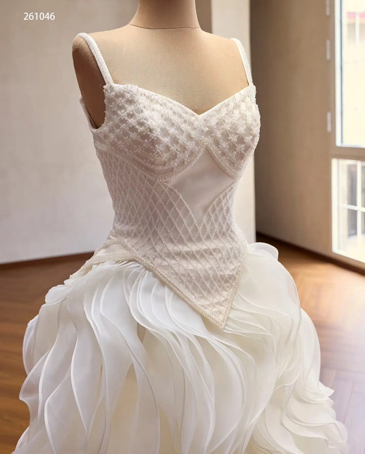 Ivory quinceañera ball gown with a diamond-beaded basque corset, sweetheart neckline, and sculptural wave ruffle skirt.