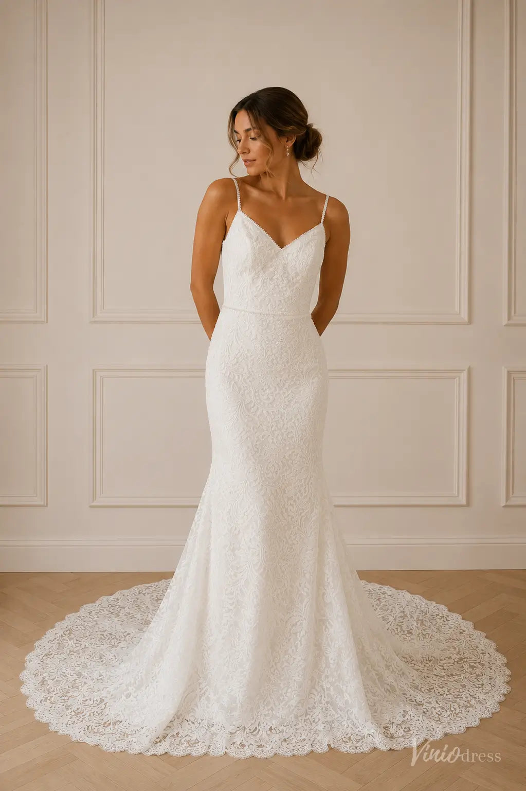 White lace mermaid wedding dress with spaghetti straps, a V-neckline, and a delicate scalloped train.