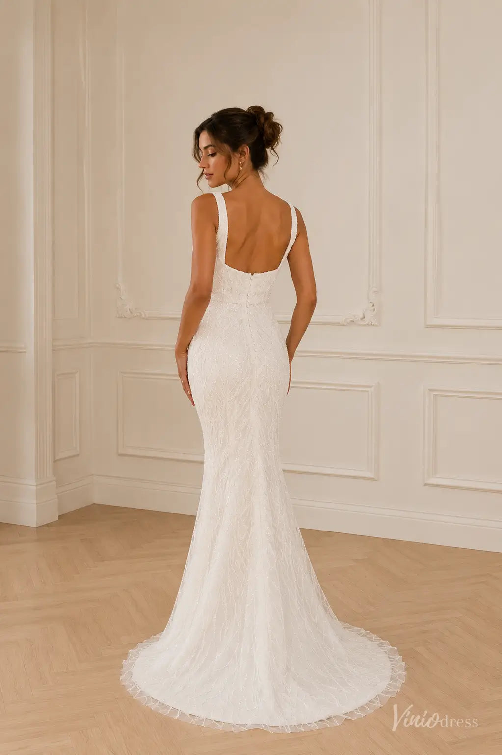White mermaid wedding dress with square neckline, intricate lace detailing, and a low back with button closure.