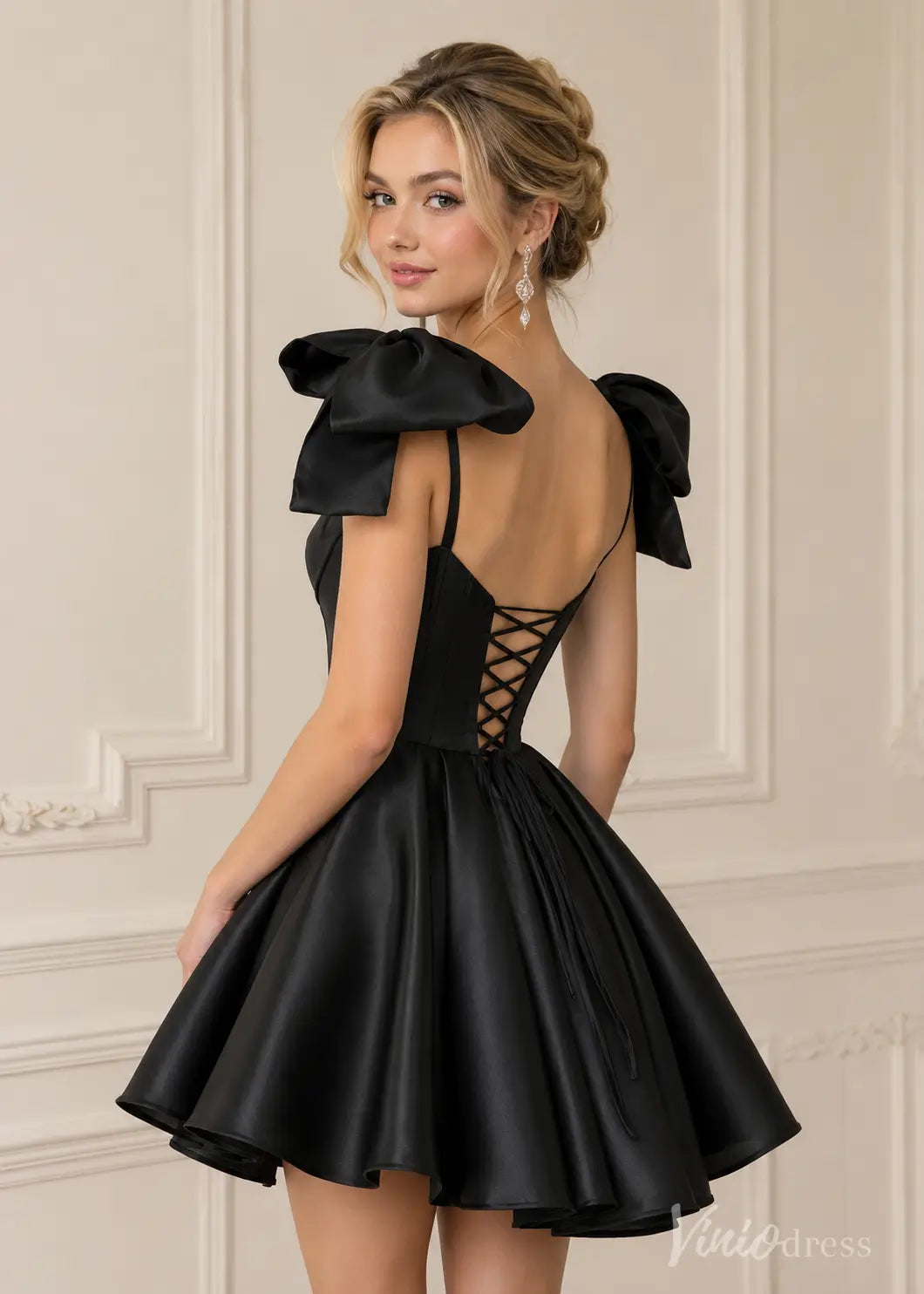 Black satin mini dress with large shoulder bows, spaghetti straps, and a lace-up corset back.