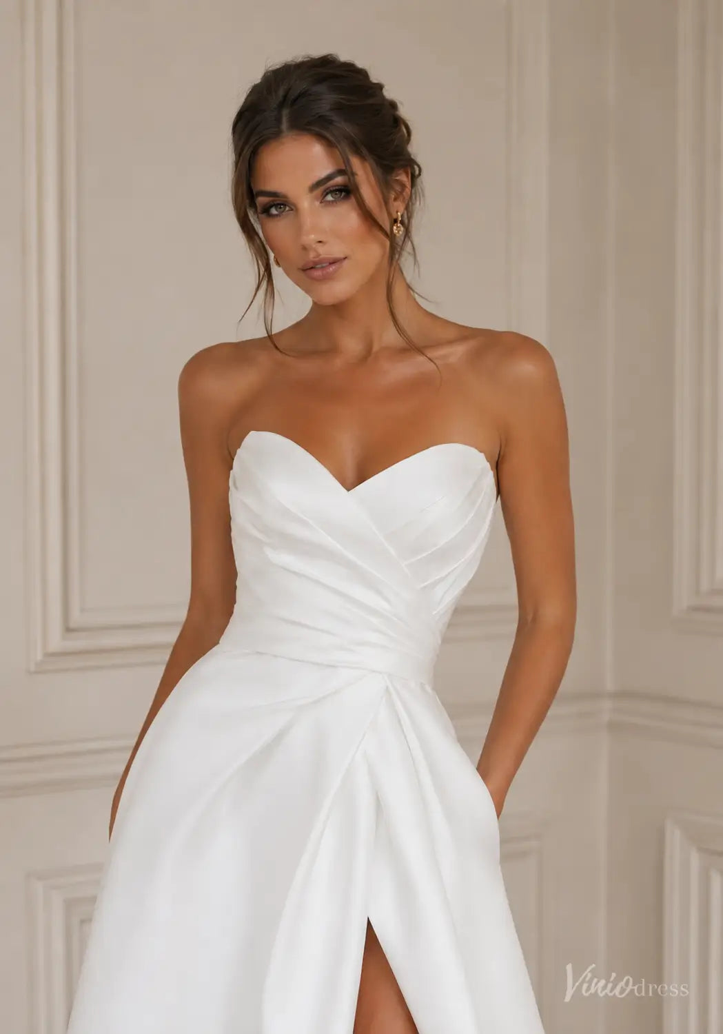 Minimalist white satin wedding dress with a strapless sweetheart neckline, ruched bodice, and high leg slit.