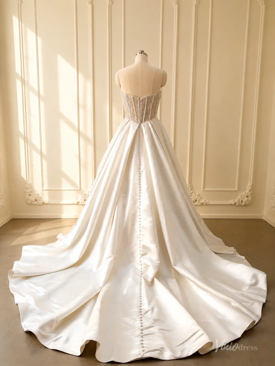 Back view of a strapless satin ball gown wedding dress with a pearl-beaded corset and chapel train.