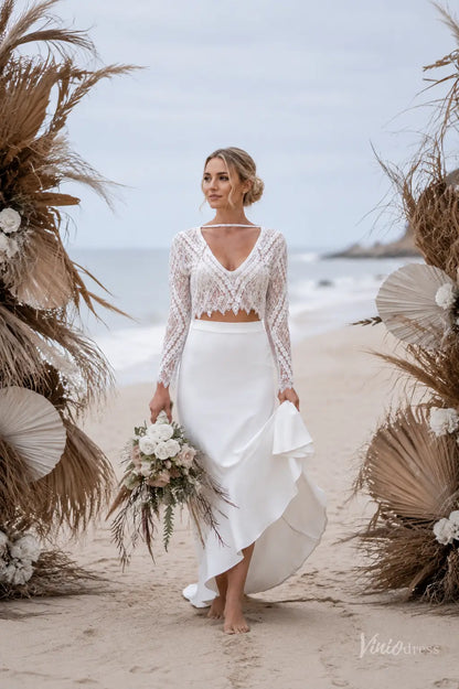 Two-piece boho wedding dress with long-sleeve lace top and high-low crepe skirt on a beach bride.