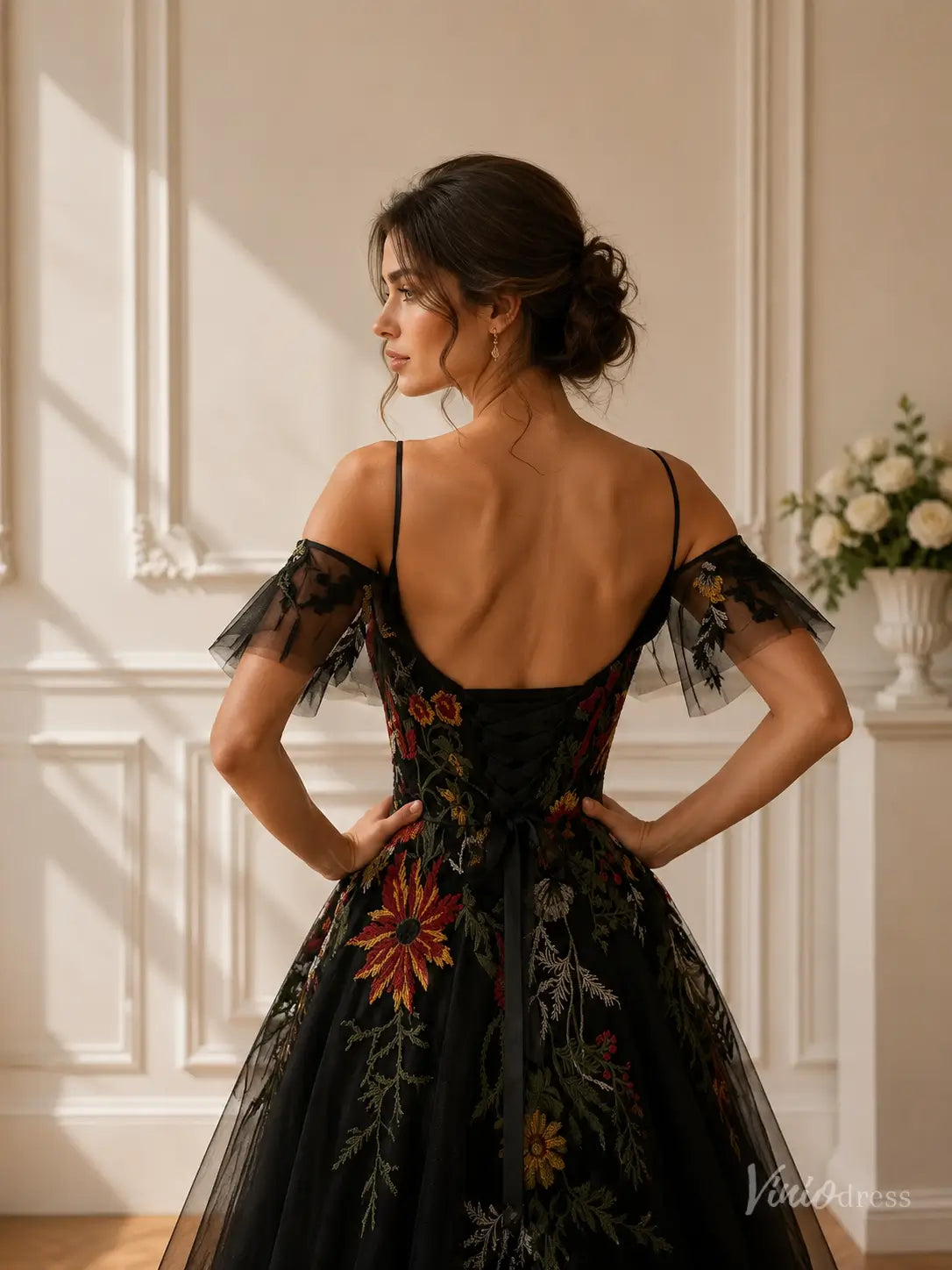 Black A-line wedding dress with colorful floral embroidery, cold shoulder sleeves, spaghetti straps, and corset back.