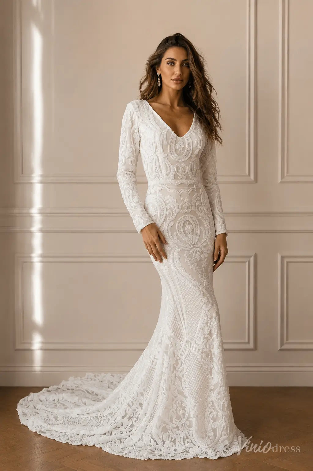 White long-sleeve mermaid wedding dress featuring intricate lace embroidery, a deep V-neckline, and a sweeping train.
