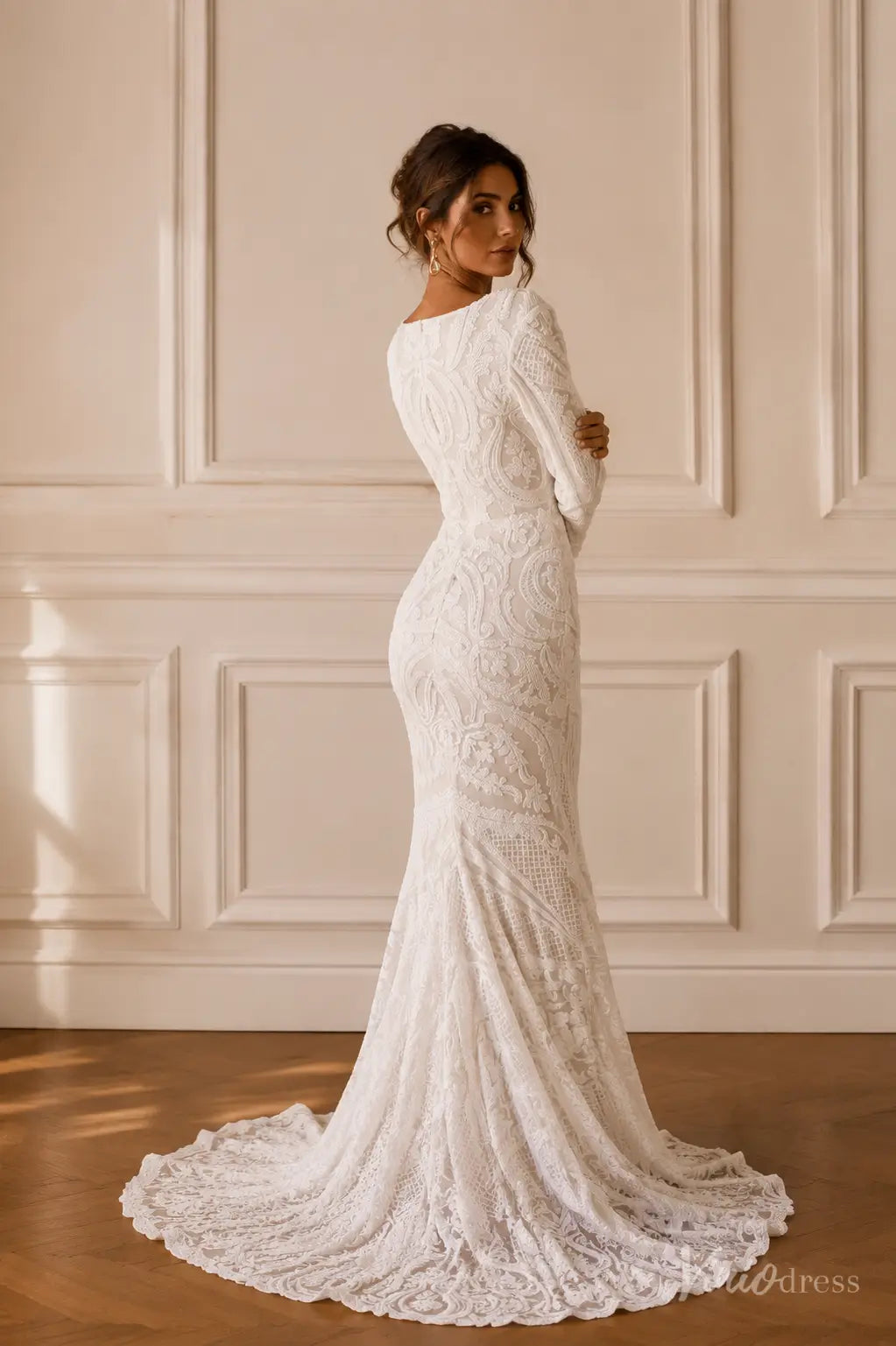 White long-sleeve mermaid wedding dress with intricate lace detailing and a sweeping train.