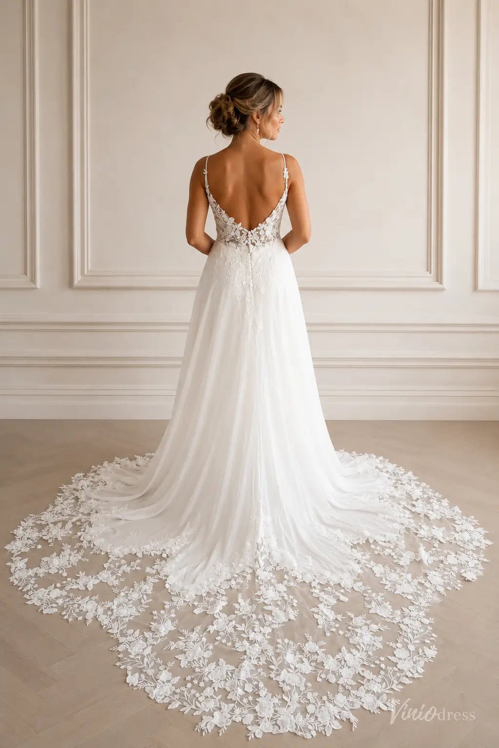 White A-line wedding dress with a low back, spaghetti straps, and a long floral lace train.