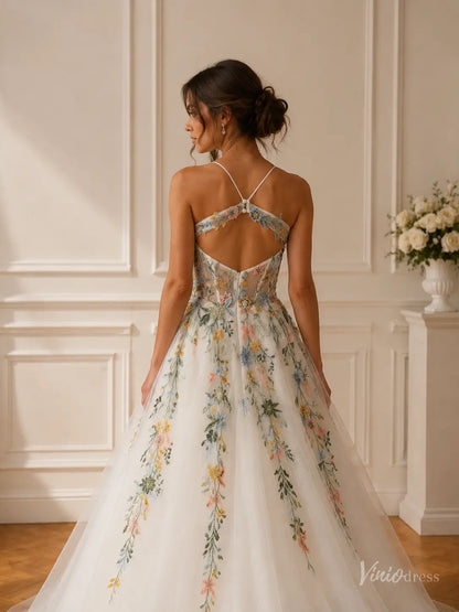 Open-back wedding dress with colorful floral embroidery, spaghetti straps, and a shimmering glitter tulle skirt.