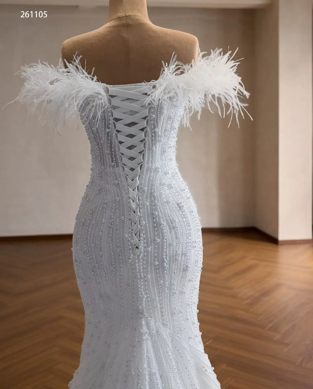 White mermaid wedding dress with feather off-shoulder neckline, pearl-beaded bodice, and lace-up corset back.