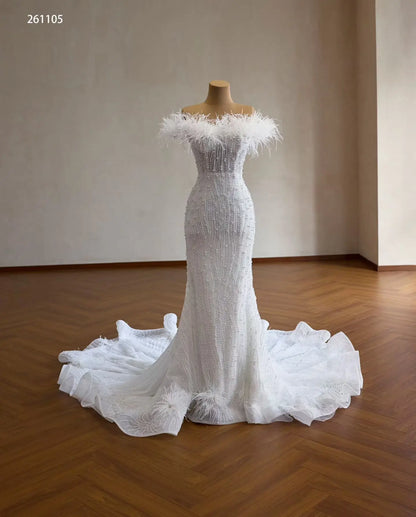 White mermaid wedding dress with feather off-shoulder neckline, vertical pearl beading, and ruffled flared hem.