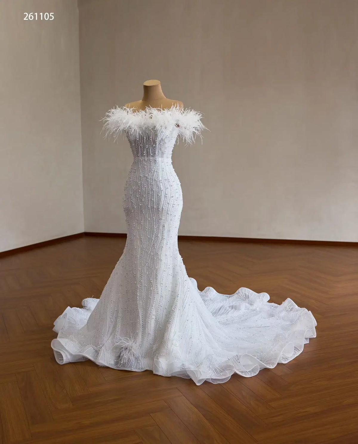 White mermaid wedding dress with feather-trimmed off-shoulder neckline, vertical pearl beading, and ruffled flared hem.