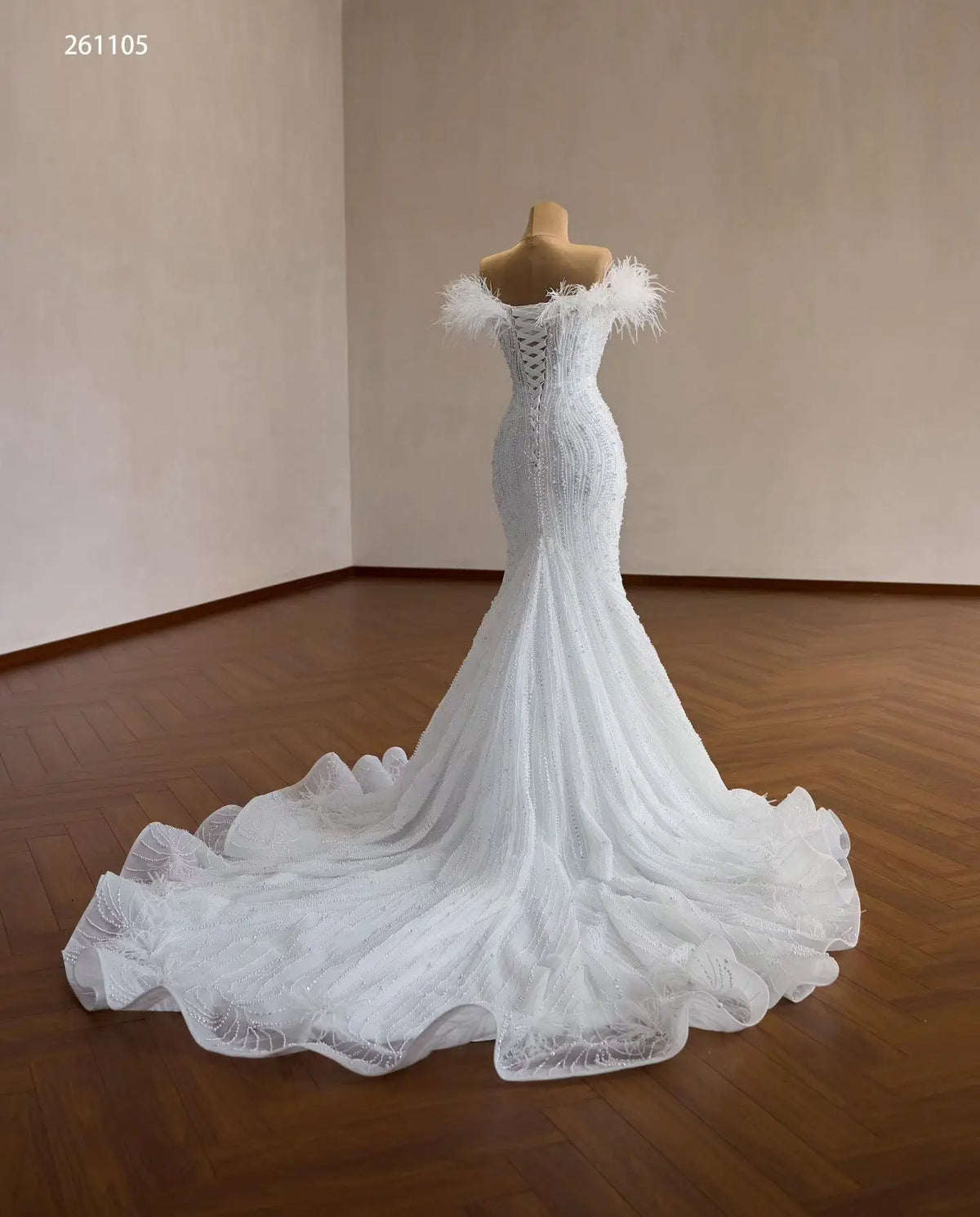 White mermaid wedding dress with pearl beading, feather-trimmed off-shoulder neckline, and lace-up corset back.