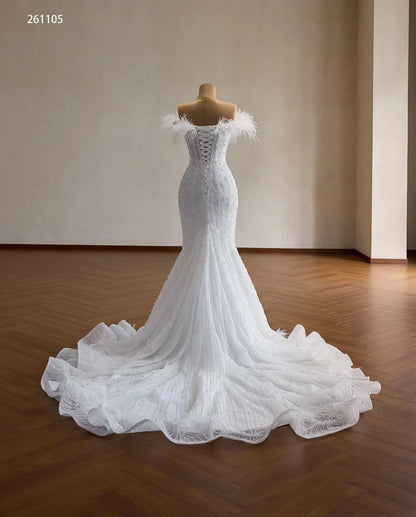 White mermaid wedding dress with feather-trimmed off-shoulder neckline, beaded vertical detailing, and corset lace-up back.