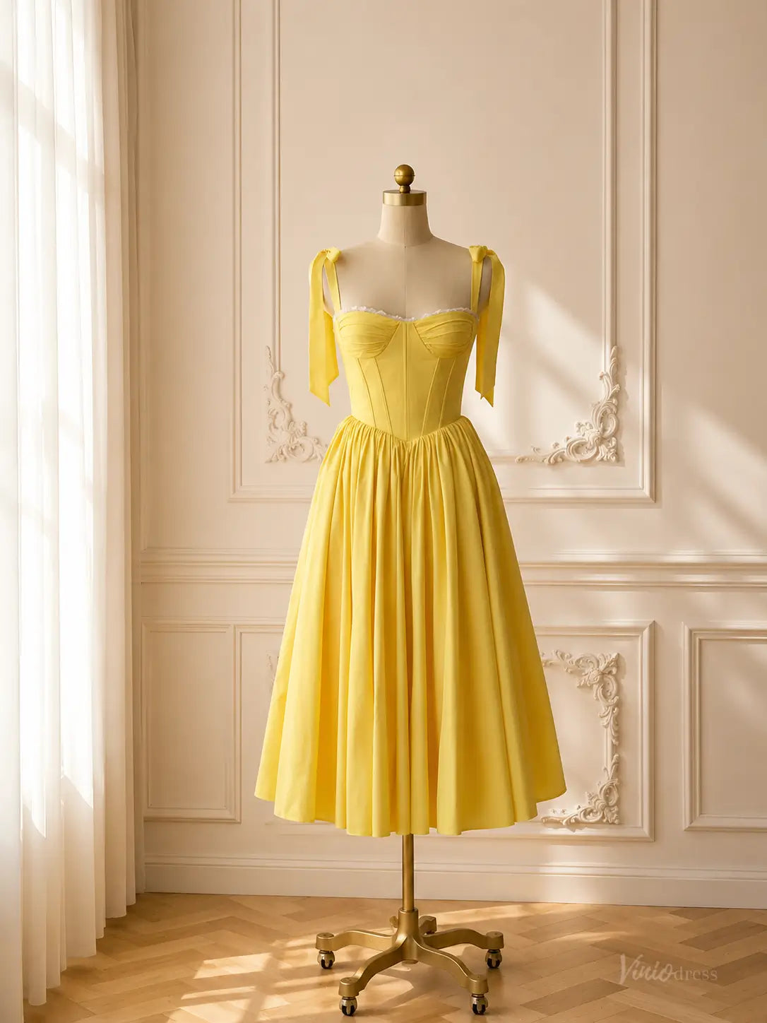 Yellow tea-length prom dress with a corset bodice, bow-tie straps, and a full A-line skirt on a mannequin.